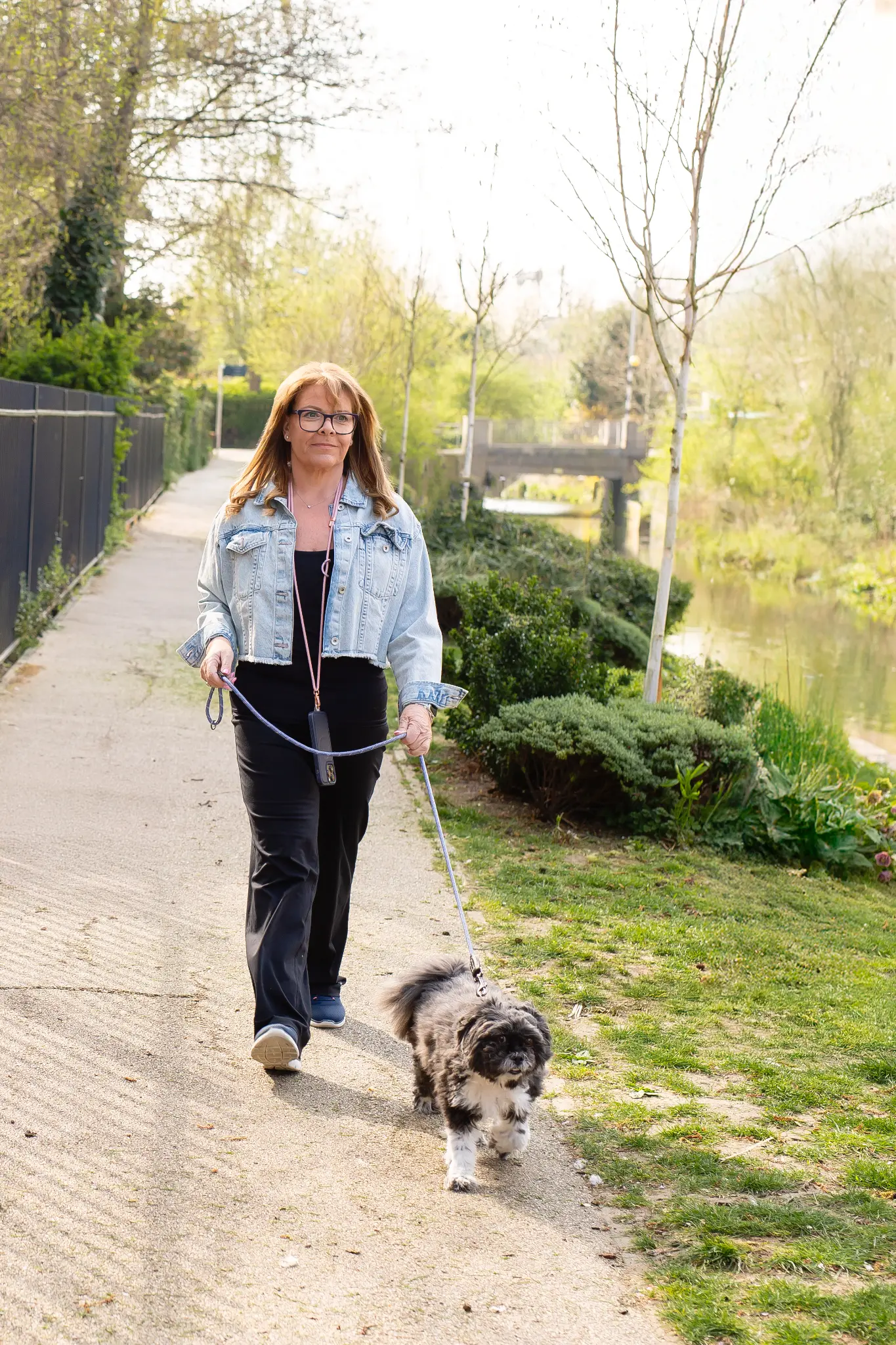 Mel walking her dog beside the water, now