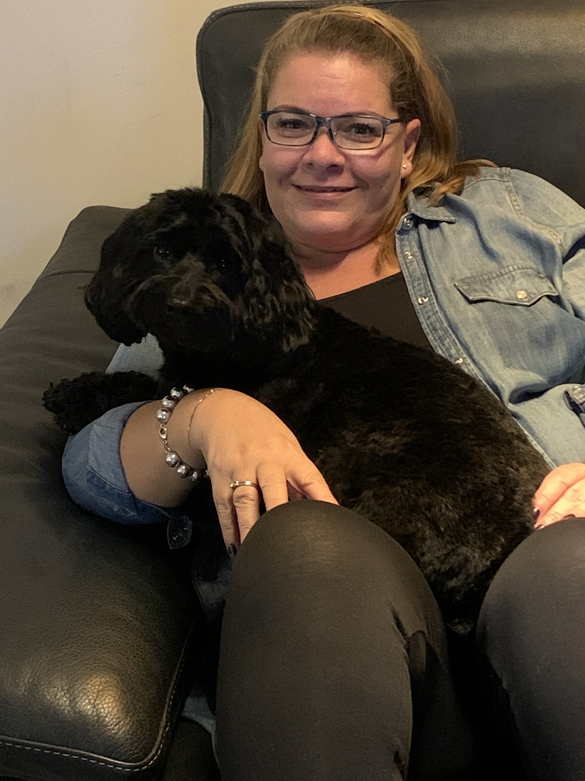 Mel sitting on a sofa with her dog, before